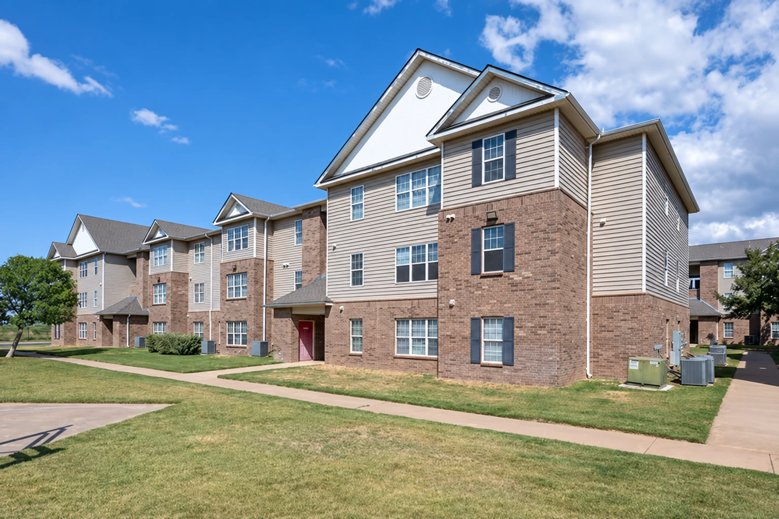 Apartment buildings with brick and light siding beside a landscaped courtyard